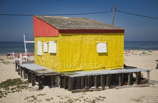 Невеликий барвистий будинок з бурхливими стінами, розташований на піщаному узбережжі з блакитним небом на фоні сонячного дня — стокове фото
