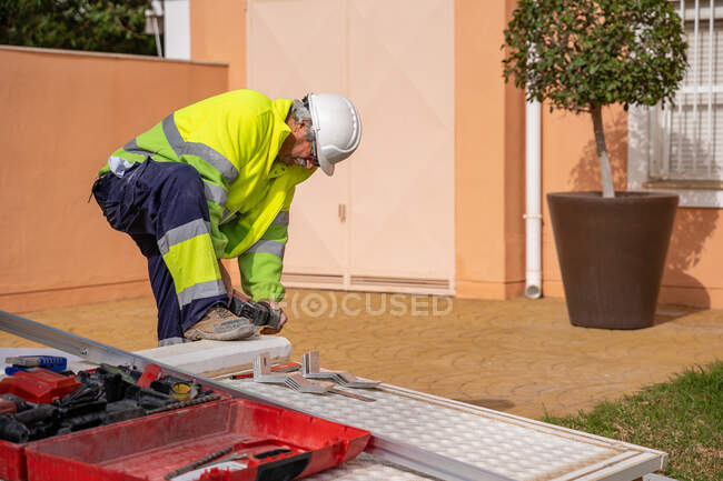Group of male technicians in uniform working with alternative solar panels and preparing for installation near residential building — Stock Photo