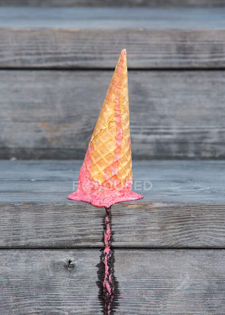 Dall'alto di gelato rosa in cono di wafer caduto su tavolino di legno con tracce di fusione — Foto stock
