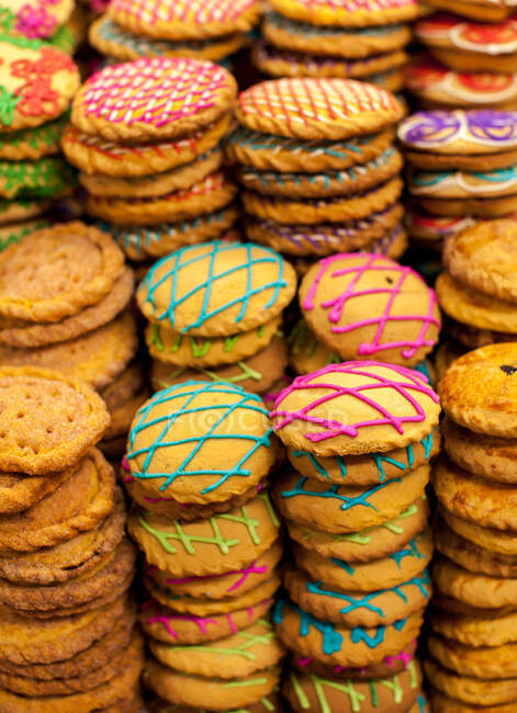 Desde arriba primer plano de galletas dulces apiladas decoradas con glaseado colorido en la mesa - foto de stock