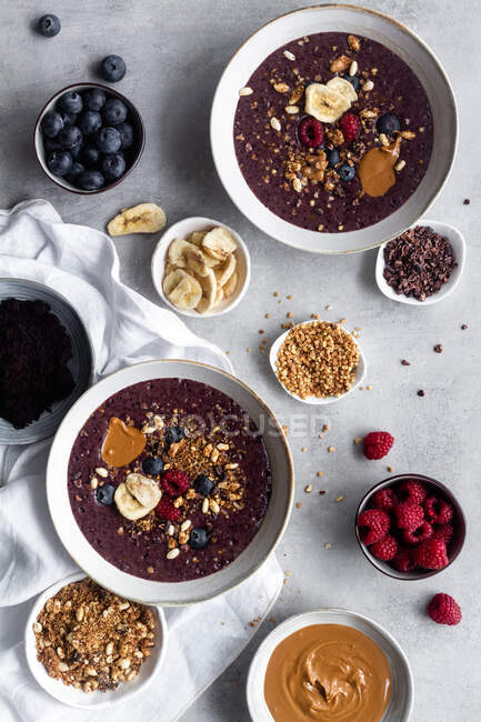 Top view composition with served for breakfast acai bowls on marble table with ingredients for recipe including nuts and cereals with fresh berries and caramel — Stock Photo