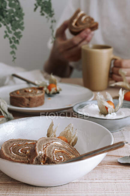Dall'alto di affettati deliziosa torta dolce fatta in casa con panna montata e Physalis fiori secchi serviti su piatto su tavolo di legno con ingredienti — Foto stock
