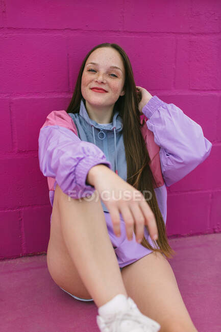 Модный подросток сидит у розовой стены — стоковое фото