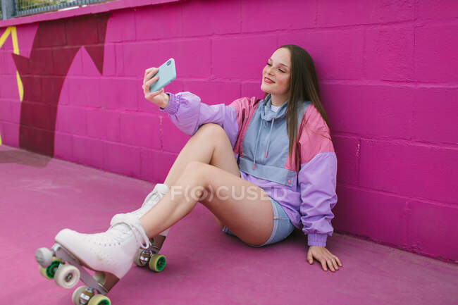Joyeux jeune femme en utilisant smartphone dans la rue et en prenant selfie — Photo de stock