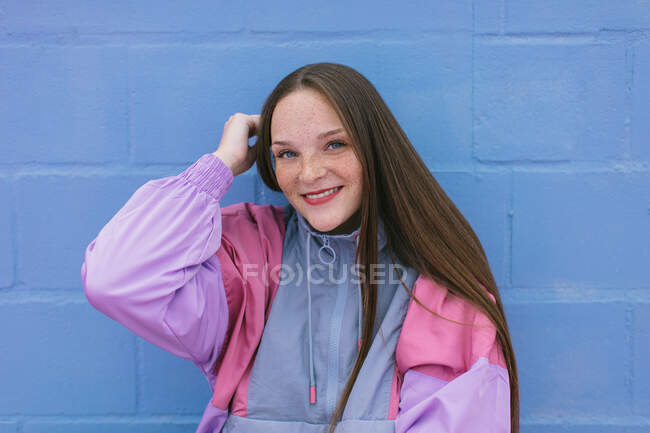 Adolescente de moda sentado cerca de la pared azul - foto de stock