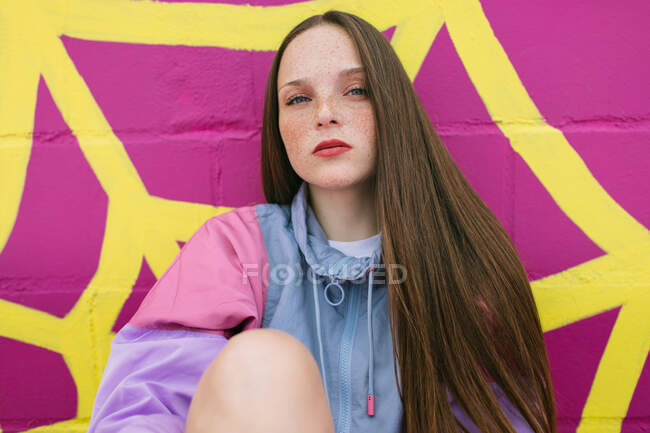 Adolescente de moda sentada cerca de la pared rosa - foto de stock