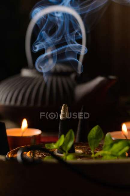 Composition of burning incense cone, teapot and candles — Stock Photo