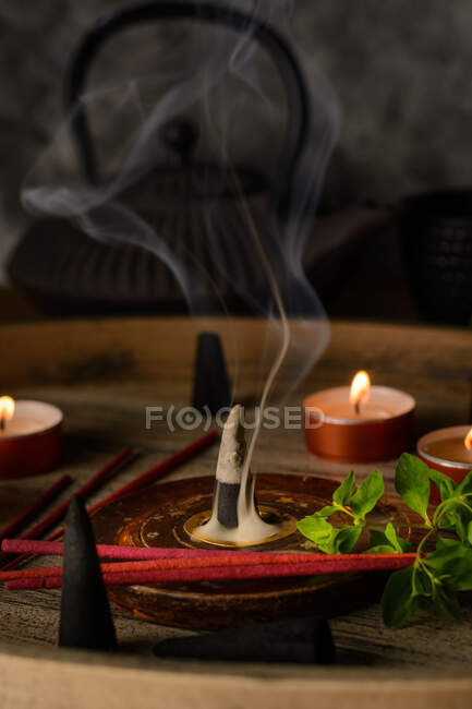 Zusammensetzung aus brennenden Räucherkegeln und Kerzen — Stockfoto