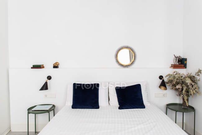 Комфортне ліжко з білим ковдрою в затишній спальні сучасної квартири — стокове фото