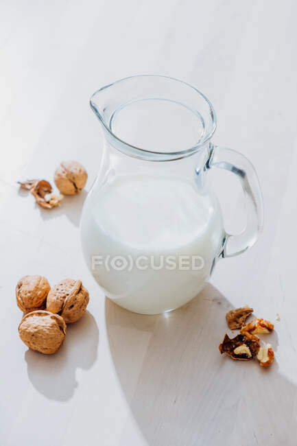 Jar of milk and nuts on table — Stock Photo