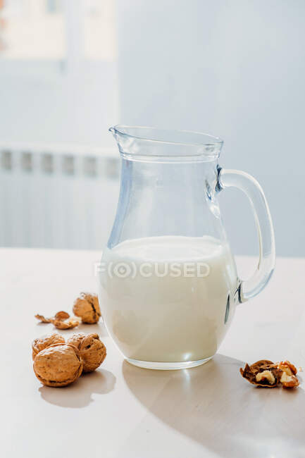 Банка молока и орехов на столе — стоковое фото