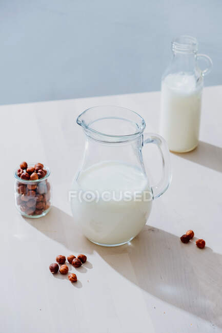 Frasco de leite e avelãs na mesa — Fotografia de Stock