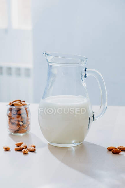 Jar of milk and almonds on table — Stock Photo