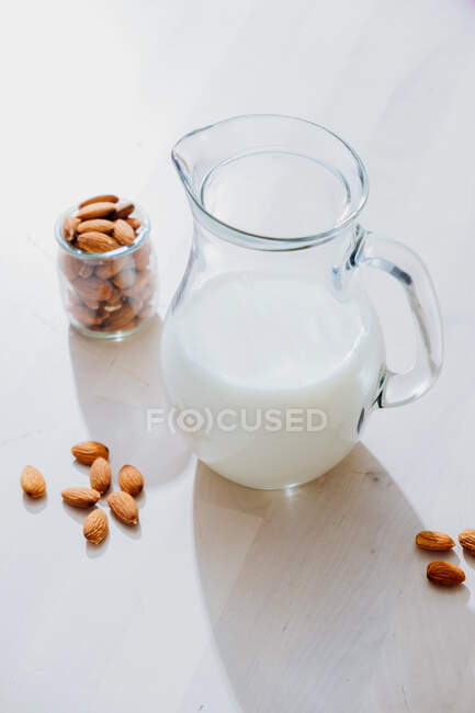 Jar of milk and almonds on table — Stock Photo