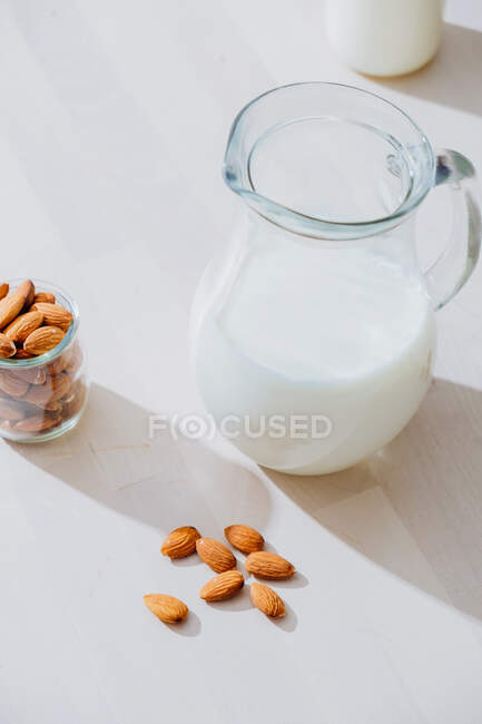 Tarro de leche y almendras en la mesa - foto de stock
