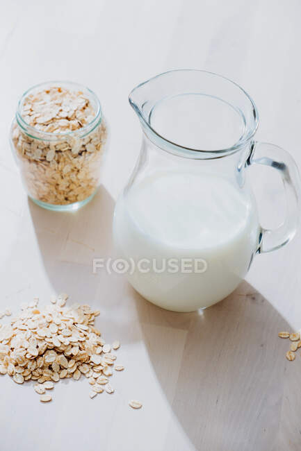 Jar of milk and oatmeal flakes on table — Stock Photo