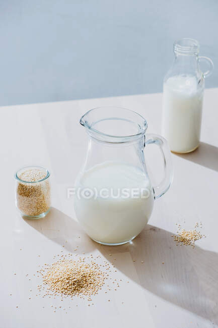 Tarro de leche y avena en la mesa - foto de stock