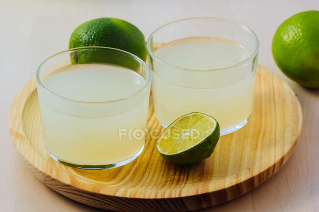 Limonada refrescante casera en vasos con lima fresca - foto de stock