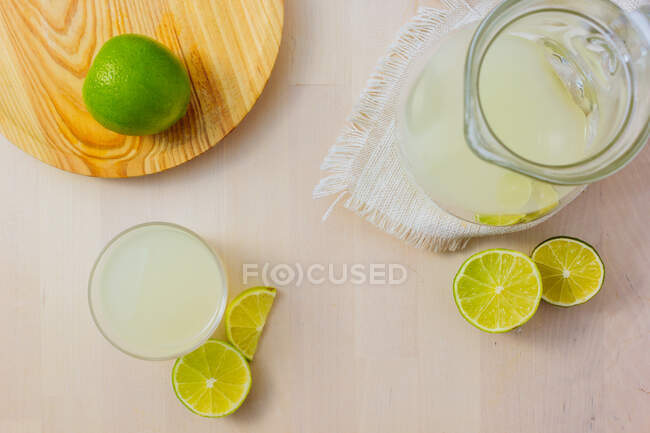 Глечик і келих домашнього освіжаючого лимонаду з нарізаним лаймом — стокове фото