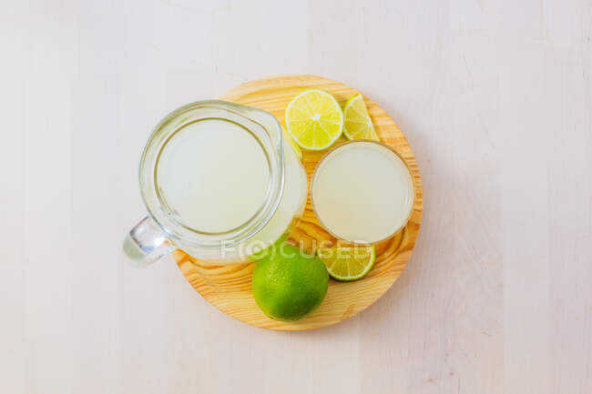 Jug and glass of homemade refreshing lemonade with sliced lime — Stock Photo