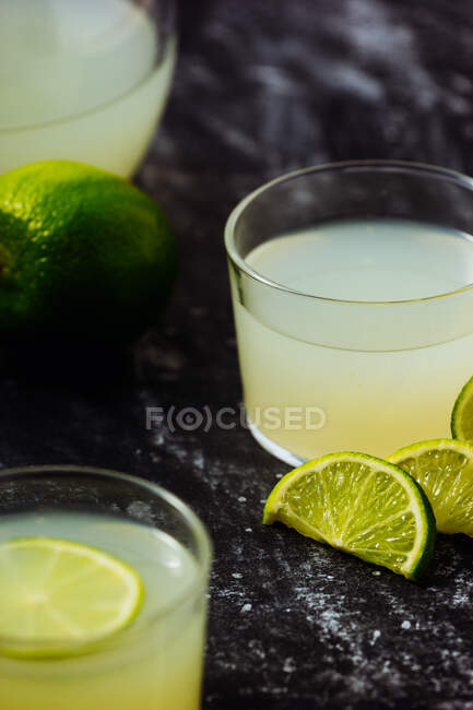 Самодельный освежающий лимонад в стаканах с ломтиками лайма — стоковое фото