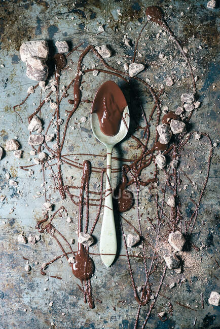 De cima colher vista superior com chocolate derramado sobre o fundo de superfície de metal rústico — Fotografia de Stock