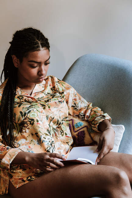 Donna etnica con libro a riposo a casa — Foto stock