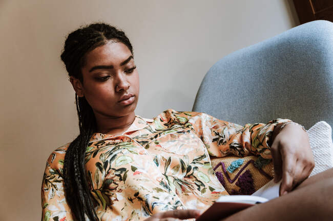 Етнічна жінка з книгою відпочиває вдома — стокове фото