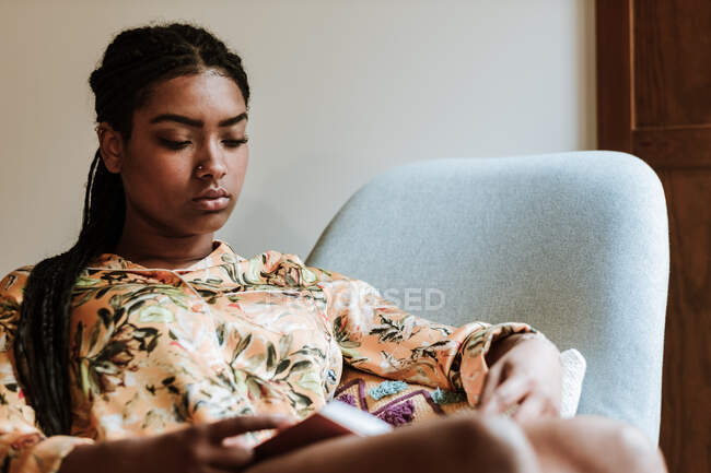 Ethnic woman with book resting at home — Stock Photo