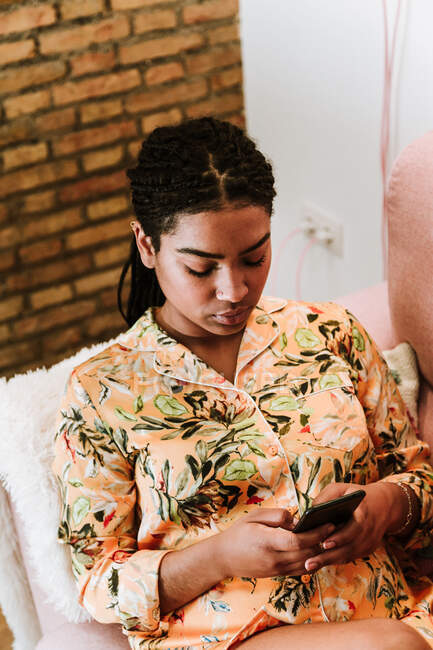 Молода жінка використовує смартфон вдома — стокове фото