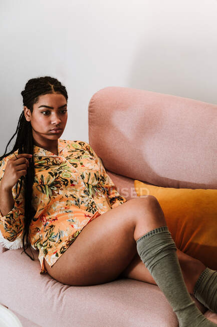 Mujer étnica pensativa sentado en la sala de estar - foto de stock
