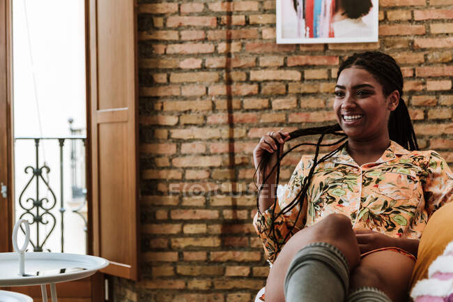 Mujer étnica feliz sentado en la sala de estar - foto de stock