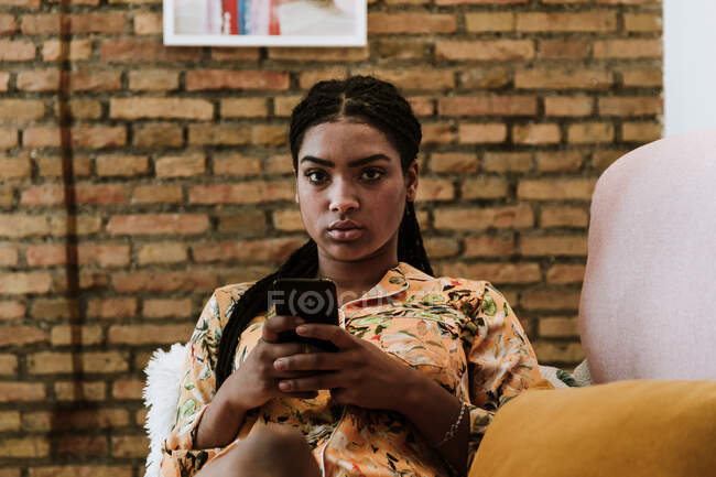 Jeune femme ethnique naviguant smartphone à la maison — Photo de stock