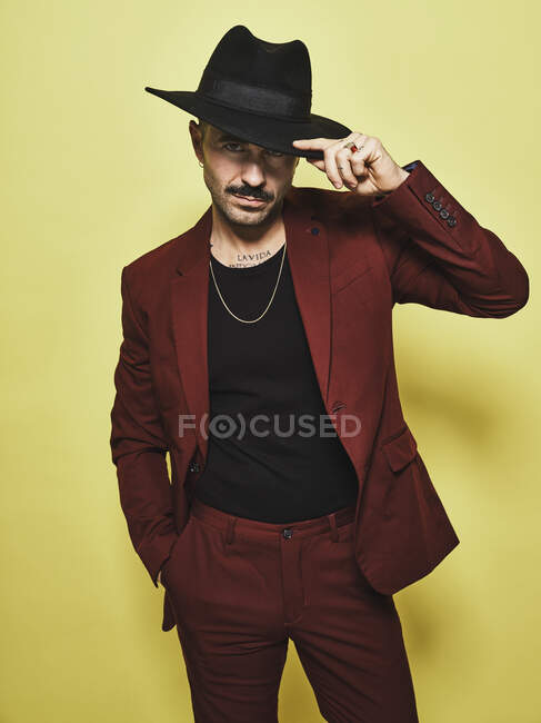 Bonito barbudo bem vestido macho na moda terno vinoso e chapéu olhando para a câmera contra fundo amarelo — Fotografia de Stock