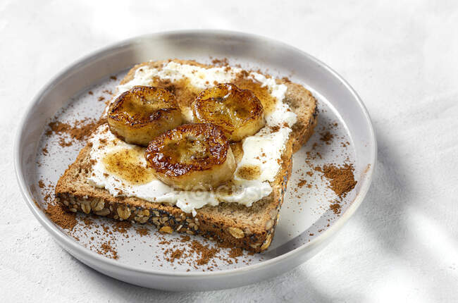 Pan tostado casero con queso crema, plátano frito, miel y canela. Comida vegetariana.. - foto de stock