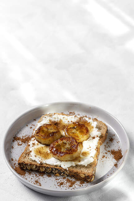 Hausgemachtes Toastbrot mit Frischkäse, gebratener Banane, Honig und Zimt. Vegetarisches Nahrungsmittel.Gesundes Ernährungskonzept. — Stockfoto