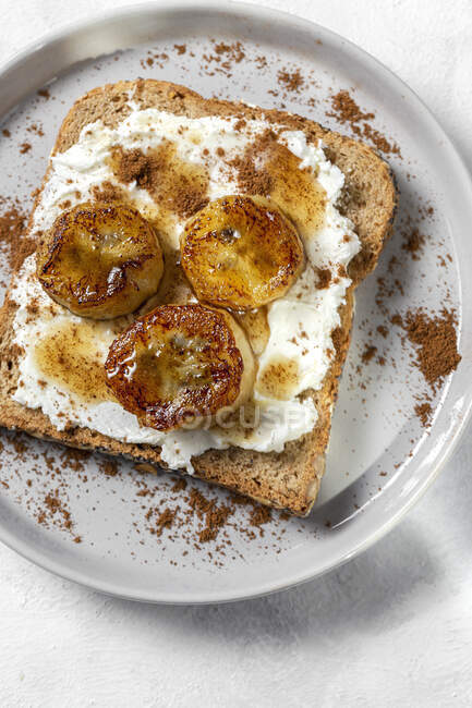 Hausgemachtes Toastbrot von oben mit Frischkäse, gebratener Banane, Honig und Zimt. Vegetarisches Lebensmittel.Gesundes Ernährungskonzept. — Stockfoto