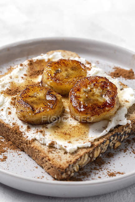 Pane tostato fatto in casa con crema di formaggio, banana fritta, miele e cannella.. — Foto stock