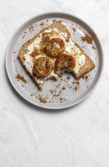 Pan tostado hecho en casa desde arriba con queso crema, plátano frito, miel y canela. Comida vegetariana.. - foto de stock