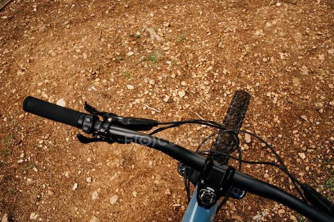 Вид зверху на сучасний велосипед, розміщений на грубому коричневому ґрунті під час подорожі по сільській місцевості — стокове фото