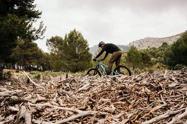 Ciclista andar de bicicleta no caminho rochoso na floresta — Fotografia de Stock