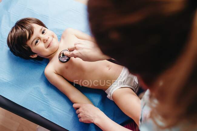 Врач со стетоскопом осматривает ребенка в клинике — стоковое фото