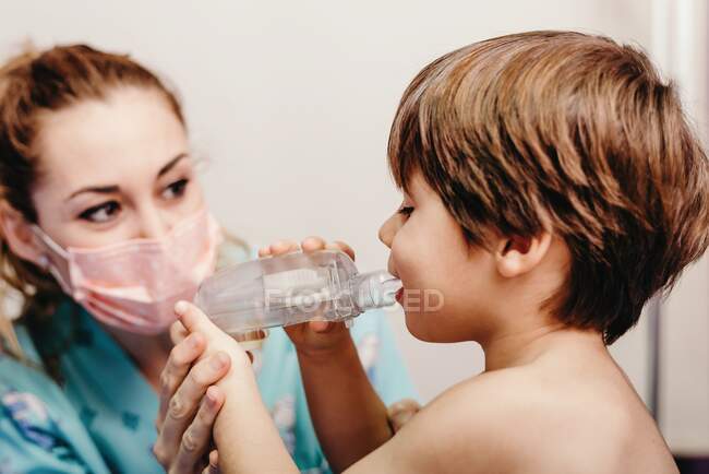Little kid using inhaler in clinic during check up — Stock Photo