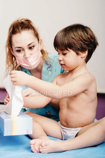Niño sonándose la nariz en el hospital en revisión - foto de stock