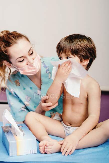 Маленький мальчик сморкается в больнице на осмотре — стоковое фото