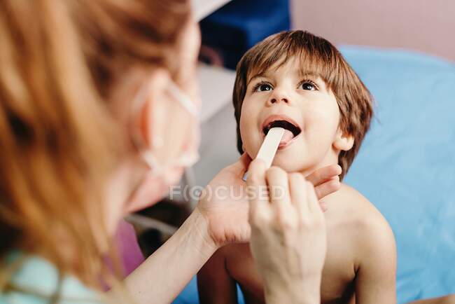 D'en haut du petit garçon avec la bouche ouverte étant examiné par une femme médecin à la clinique — Photo de stock