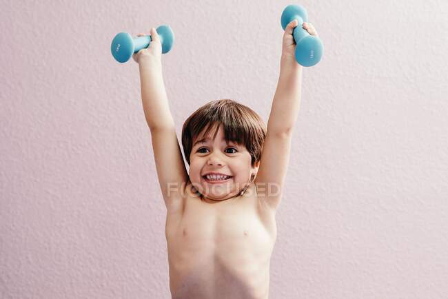 Веселый маленький мальчик с гантелями — стоковое фото