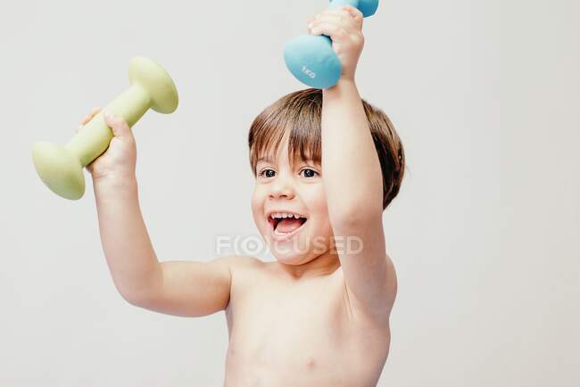Веселый маленький мальчик с гантелями — стоковое фото