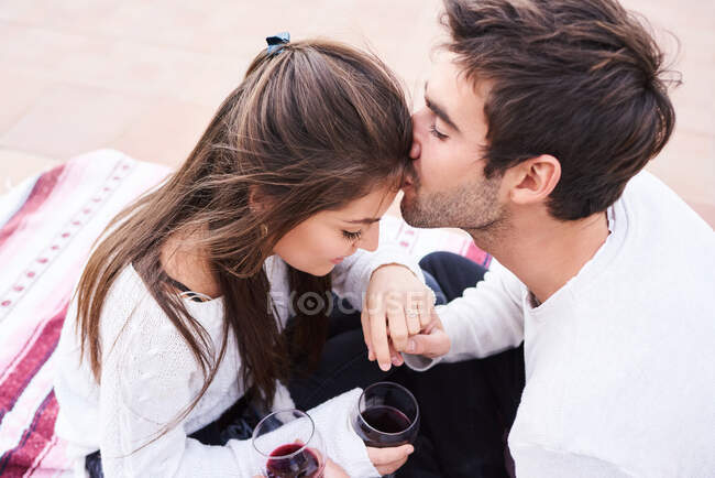 Desde arriba alegre pareja joven en ropa casual brindis con copas de vino tinto mientras disfrutan de momentos felices juntos - foto de stock
