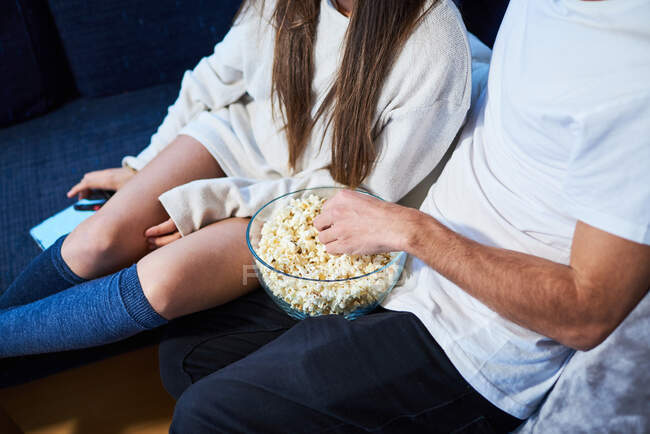 Close-up a couple eating popcorn sitting on the sofa at home — Stock Photo
